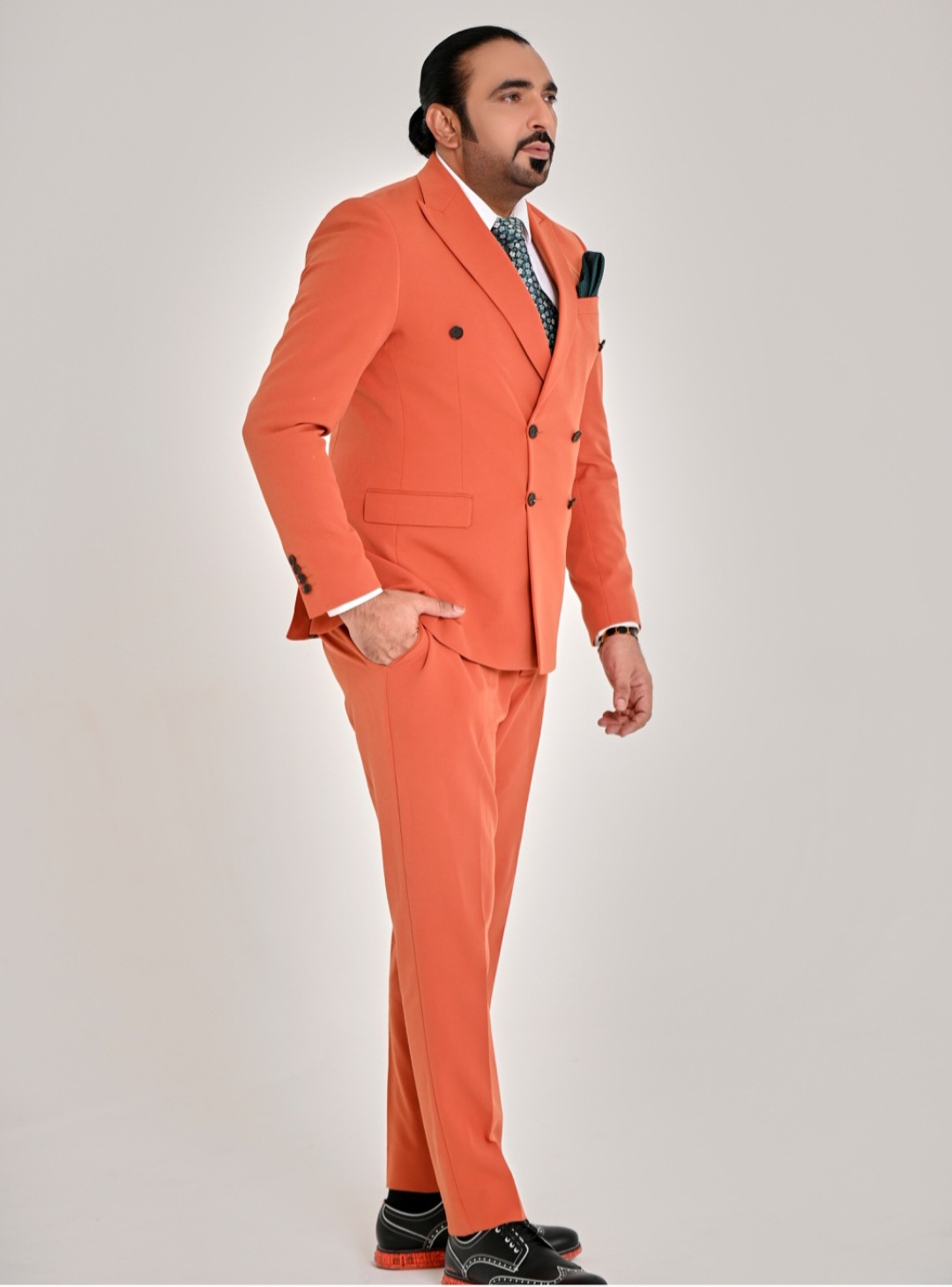 Syed Mudassar Khushnood editorial portrait in tailored orange suit